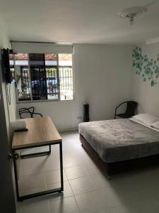 1 dormitorio con cama, mesa y ventana en Cocobamboo Hotel, en Medellín