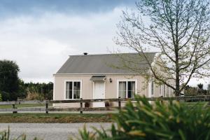 a white house with a fence in front of it at Brackenridge Country Retreat & Spa in Martinborough 