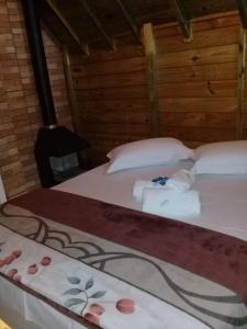 two beds in a room with towels and a stove at Chalés Snow in Urubici