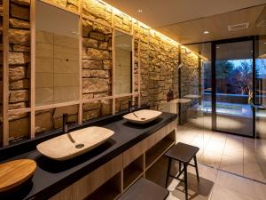 a bathroom with two sinks and a stone wall at Auberge Fontaine Bleau Atami in Atami