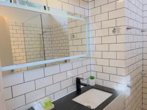 a white tiled bathroom with a sink and a mirror at Sandpiper Motel Apollo Bay in Apollo Bay