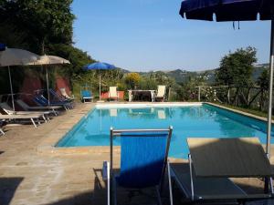 einen Pool mit Stühlen und Sonnenschirmen in der Unterkunft Belvilla by OYO Santa Caterina in Monte San Martino