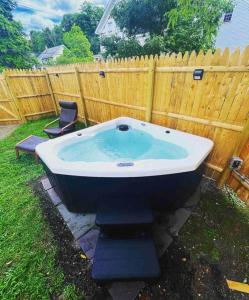 a bath tub sitting in the yard next to a fence at NEW!! Lovely unit w/ PRIVATE Hot Tub and patio! in Laconia
