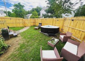 a backyard with a tub and chairs and a fence at NEW!! Lovely unit w/ PRIVATE Hot Tub and patio! in Laconia