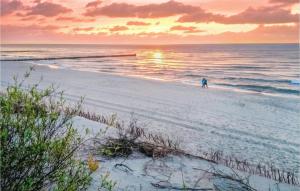 una persona caminando por la playa al atardecer en Stunning Home In Sianozety With Kitchenette, en Sianożęty