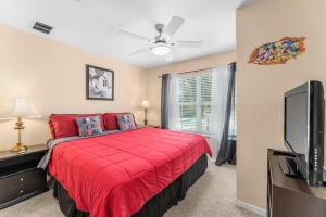 a bedroom with a red bed and a flat screen tv at Perfect for Family, Wake up Next to the pool! in Kissimmee