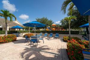 a patio with chairs and tables and blue umbrellas at Perfect for Family, Wake up Next to the pool! in Kissimmee