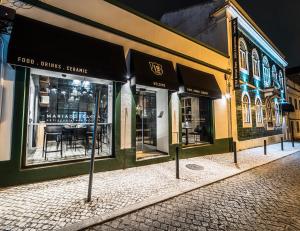 a row of store fronts on a street at night at 19 Tile Ceramic Concept - by Unlock Hotels in Caldas da Rainha