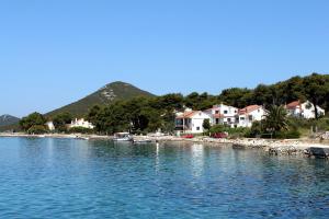 eine Gruppe von Häusern am Ufer eines Wasserkörpers in der Unterkunft Apartments by the sea Brgulje, Molat - 13318 in Molat