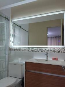 y baño con lavabo, espejo y aseo. en Departamento Full en Lince, en Lima
