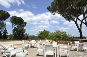 eine Reihe von weißen Tischen und Stühlen auf einer Terrasse in der Unterkunft Hotel Villa Maria Regina in Rom