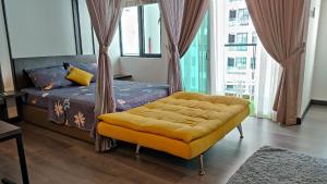 um quarto com uma cama com um repousa-pés amarelo em Hidayah Homestay near UKM and KTM station with high speed wifi - pool & river view em Bangi