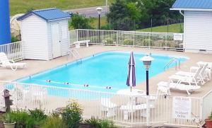 una piscina con sillas y sombrilla en Smokies Inn - New Linens & Ultrafast WIFI - Friendliest Hospitality Guaranteed!, en Kodak