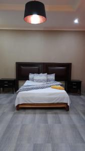 a bedroom with a large bed with a wooden headboard at Unik studio Apartments in Lusaka