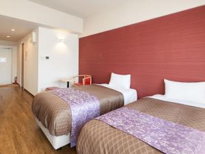 読谷村にあるミチ旅ホテル 読谷の赤い壁の客室で、ベッド2台が備わります。
