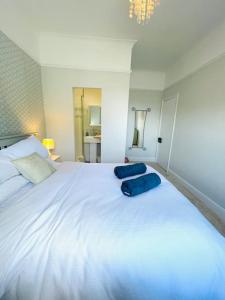a large white bed with two blue pillows on it at Pirates Place Ventnor Esplanade Beach and Sea Views in Ventnor