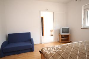 un salon avec une chaise bleue et une télévision dans l'établissement Apartment Metajna 527f, à Metajna