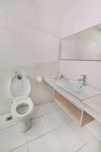 een witte badkamer met een toilet en een wastafel bij The Salak Style Hotel in Denpasar
