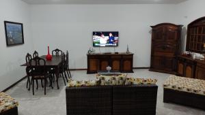 里約達斯奧斯特拉斯的住宿－Praia Virgem Hostel，客厅配有椅子、桌子和电视