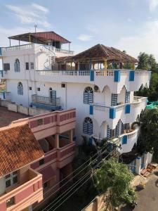een groot wit gebouw met blauwe ramen en balkons bij Holi-Wood Guesthouse in Pondicherry