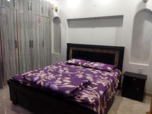 a bedroom with a bed with a purple comforter at Furnished Private Ground Floor - Pasha House in Lahore