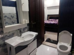 a bathroom with a sink and a toilet and a bed at Furnished Private Ground Floor - Pasha House in Lahore