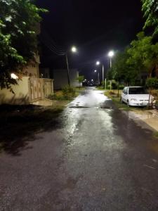 an empty street at night with a white car parked at Furnished Private Ground Floor - Pasha House in Lahore