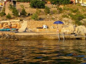 a person standing under an umbrella next to the water at Apartments by the sea Prizna, Senj - 17309 in Senj
