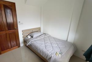 a small bed in a room with a wooden door at YYK Holiday Rooms in Ban Khlong Krang