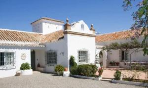 une grande maison blanche avec un toit dans l'établissement Cortijo Correa, à Marbella