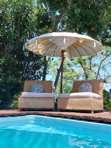 2 Stühle mit Sonnenschirm neben einem Pool in der Unterkunft La Villa Zen in Saint-Paul