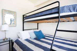 1 dormitorio con litera y colchón de rayas azul y blanco en The Corner Cottage en Mollymook