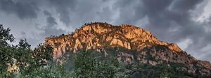 a rocky mountain with the sun shining on it at Apartament TIMEEA Baile Herculane in Băile Herculane