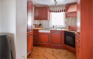 eine Küche mit roten Schränken, einem Waschbecken und einem Fenster in der Unterkunft 4 Bedroom Nice Home In Sjusjøen in Sjusjøen