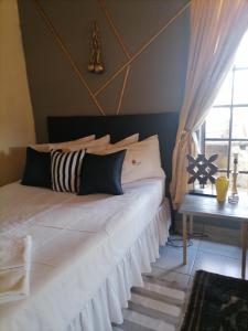 - une chambre avec un grand lit blanc et une fenêtre dans l'établissement Matlapeng Country Estate, à Vanderbijlpark
