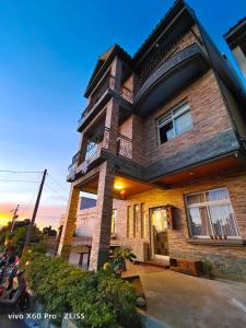 a large brick house with a sunset in the background at 白海民宿 Lunar Mare Inn in Xiaoliuqiu