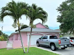 a truck parked in front of a pink house with two palm trees at Cape Canaveral near Beach House in Cape Canaveral