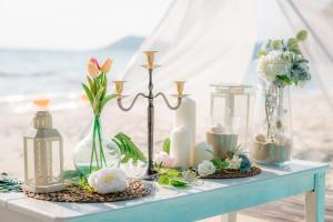 een tafel met vazen, kaarsen en bloemen erop bij Kerala Coco Resort in Ko Samed