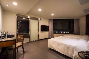 una camera d'albergo con letto, scrivania di Hotel J Taoyuan a Pingzhen