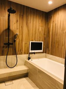 a bathroom with a tub and a tv on the wall at Villa the Club Karuizawa in Naganohara