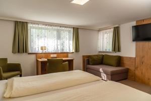 pokój hotelowy z łóżkiem, kanapą i telewizorem w obiekcie Appartements-Pension Lindenheim w Schladming