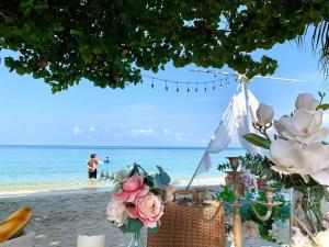 a table on the beach with flowers and people in the water at Kerala Coco Resort in Ko Samed