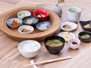 a wooden table with bowls of food and chopsticks at Mitsui Garden Hotel Kashiwa-no-ha Park Side - Chiba in Kashiwa
