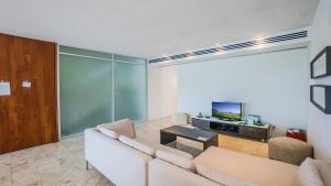 a living room with a white couch and a tv at Magia Beachside Apartment by BVR in Playa del Carmen