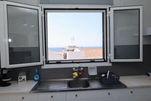 een keuken met 3 ramen en een wastafel met uitzicht bij Beautiful apartment in Plomari in Plomarion