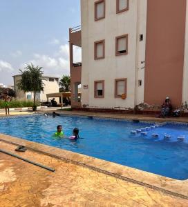 maison du bonheur en bord de mer avec piscine في السعيدية: طفلين في مسبح بجانب مبنى