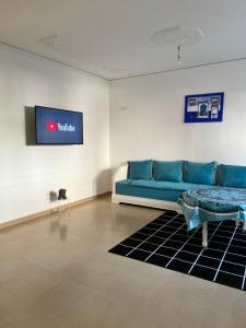 ein Wohnzimmer mit einem blauen Sofa und einem TV in der Unterkunft maison du bonheur en bord de mer avec piscine in Saidia 