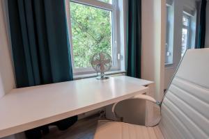 a room with a desk with a window and a fan at 4-Zimmer Wohnung mit grandioser Aussicht in zentraler Lage in Hannover