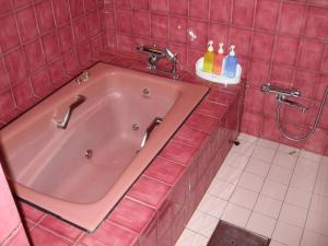 uma banheira cor-de-rosa numa casa de banho em azulejos cor-de-rosa em キャッスル24 em Hanno