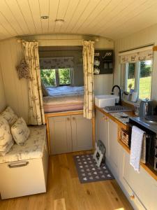 uma pequena cozinha com uma cama numa pequena casa em The Orchard Shepherds Hut em Axminster